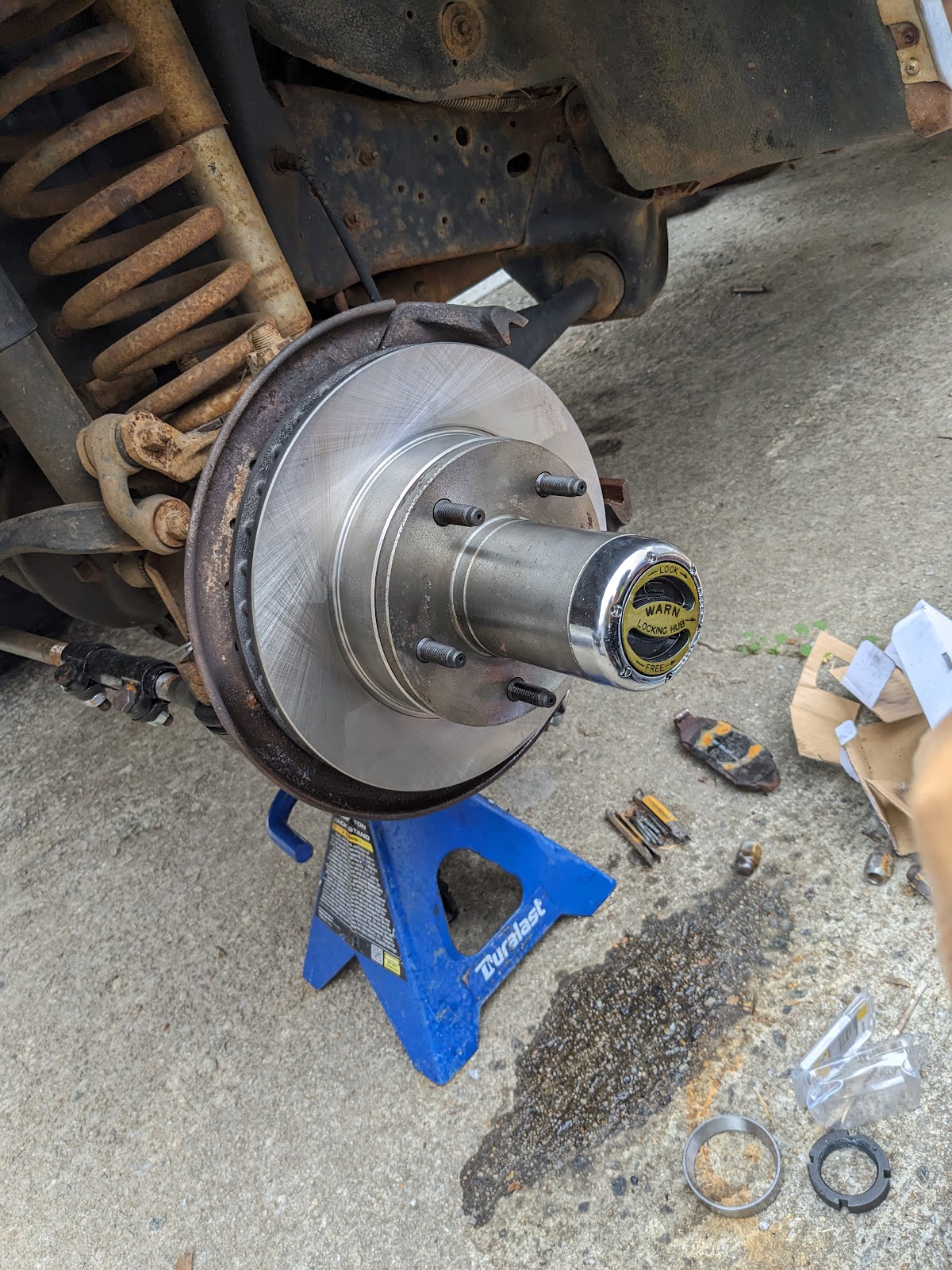Robert's Mobile Services — front brake rotor and Warn locking hub removed and set on a blue Duralast jack stand during a brake service